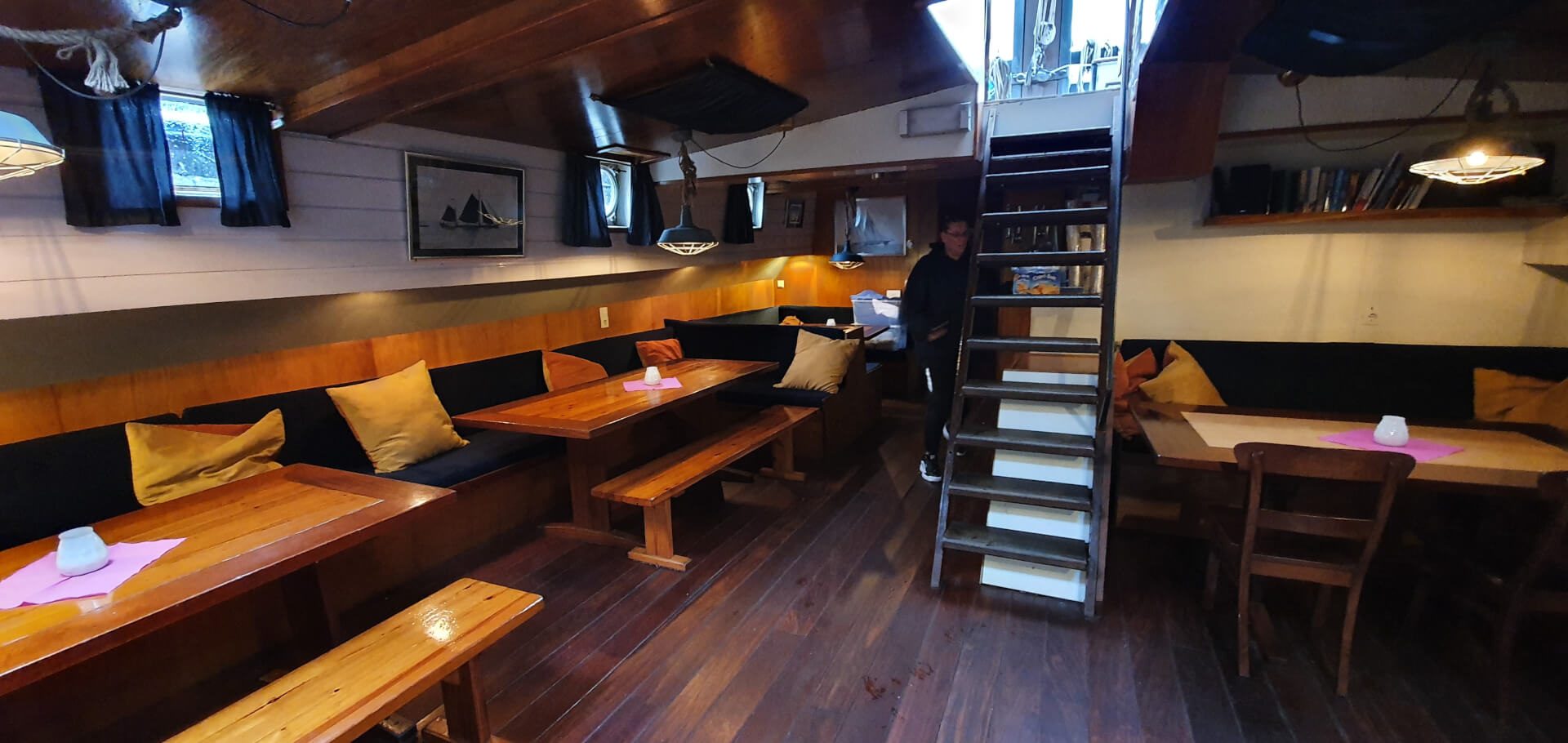 The warm saloon on board with long tables and wooden benches