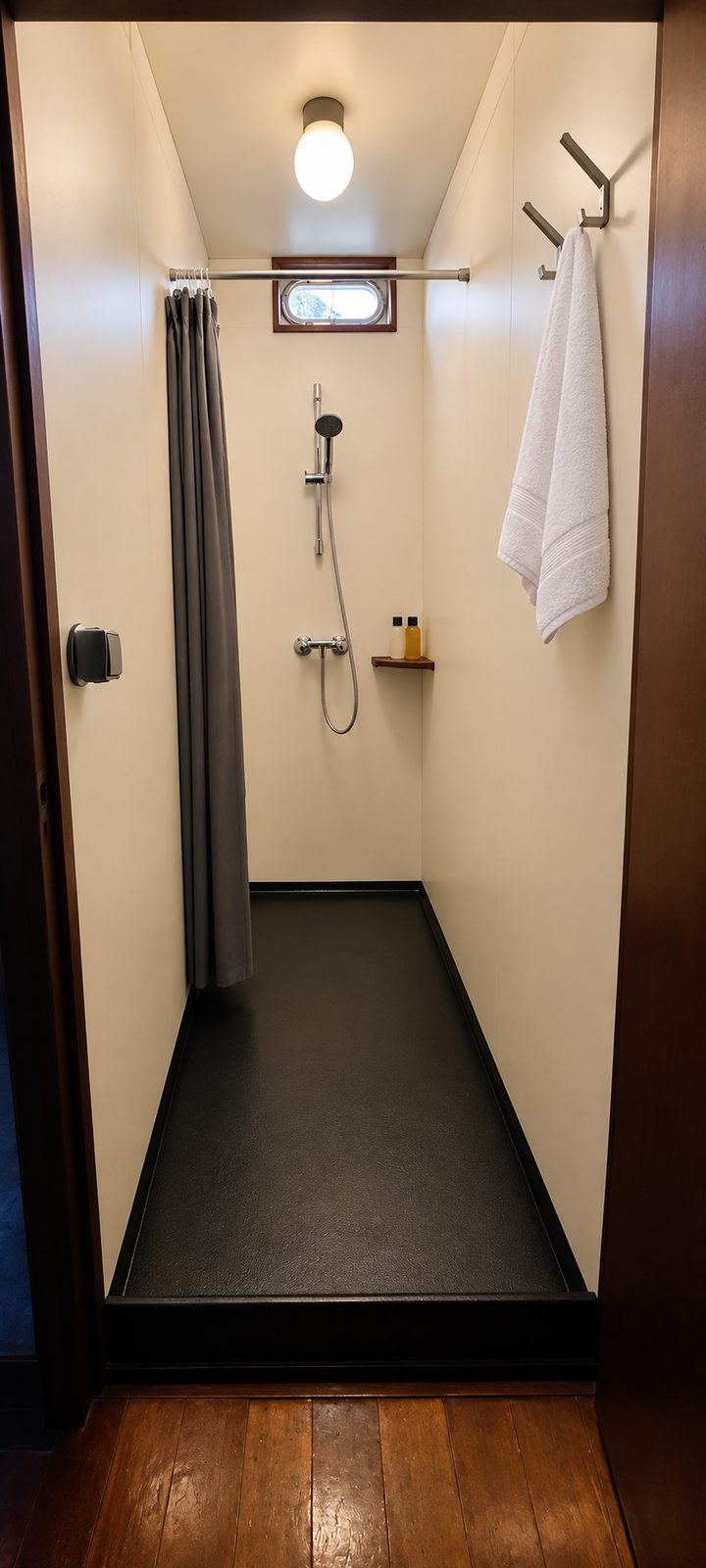 Doucheruimte aan boord met handdouche en patrijspoort